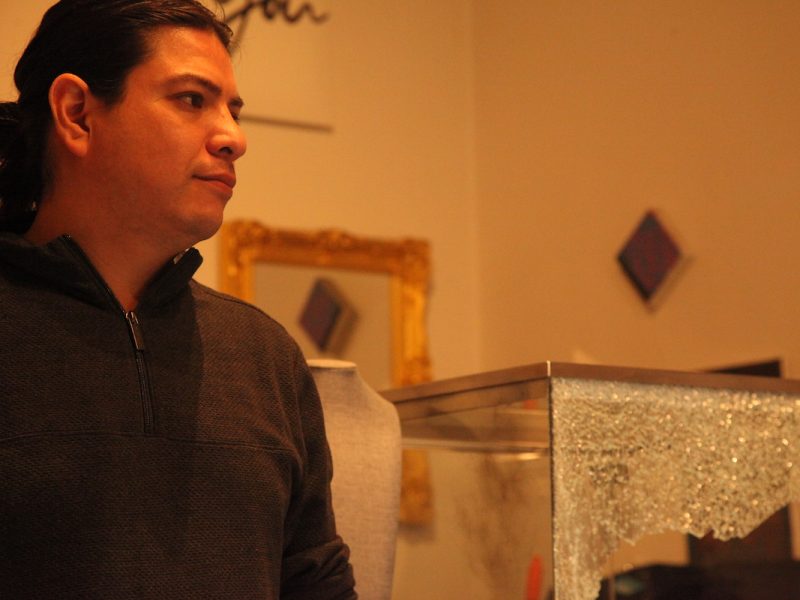 A man standing in front of a smashed glass display case.