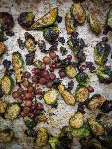 Roasted brussels sprouts and grapes on a baking sheet.