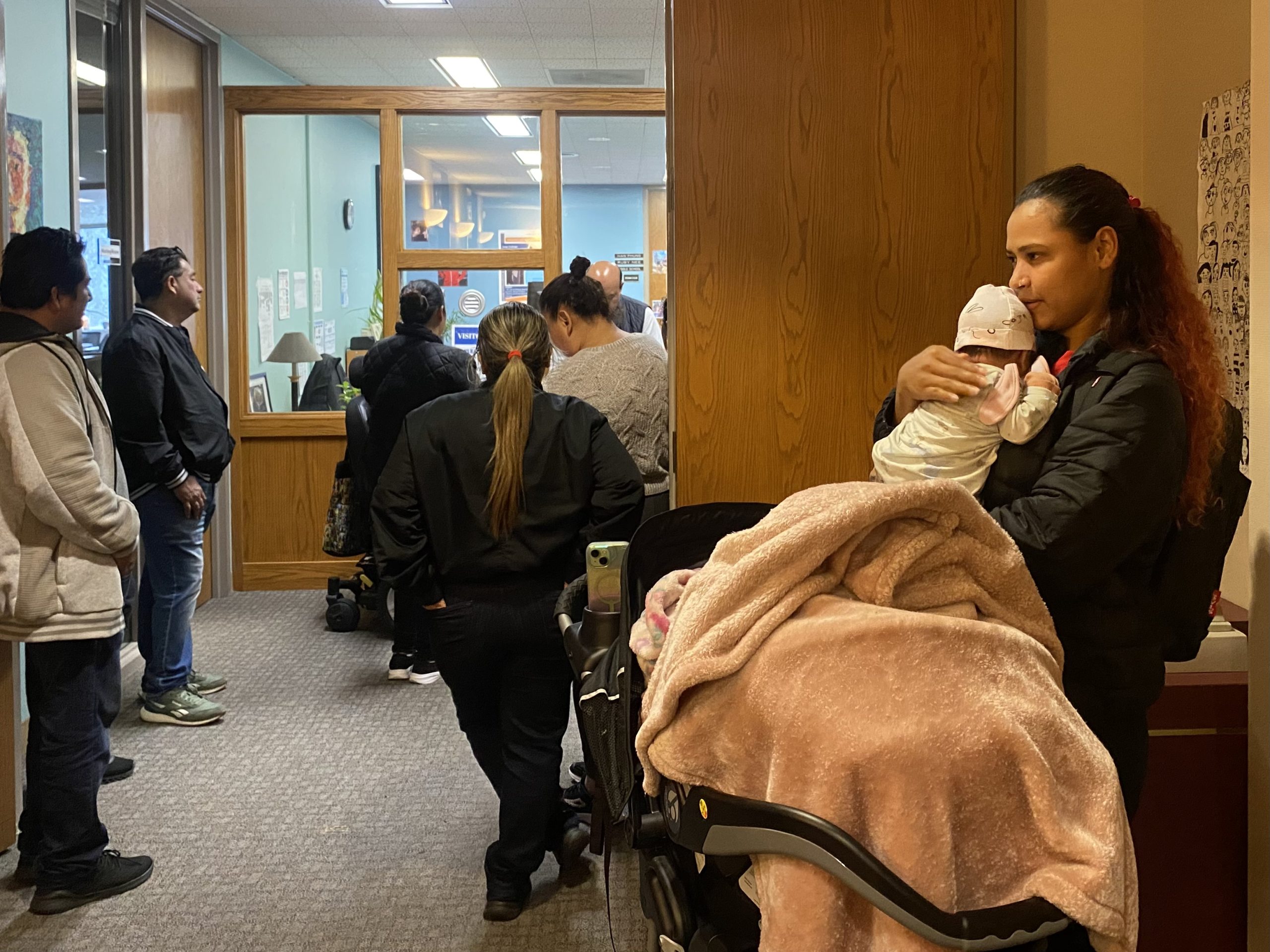 A group of people in a waiting room with a baby in a stroller.