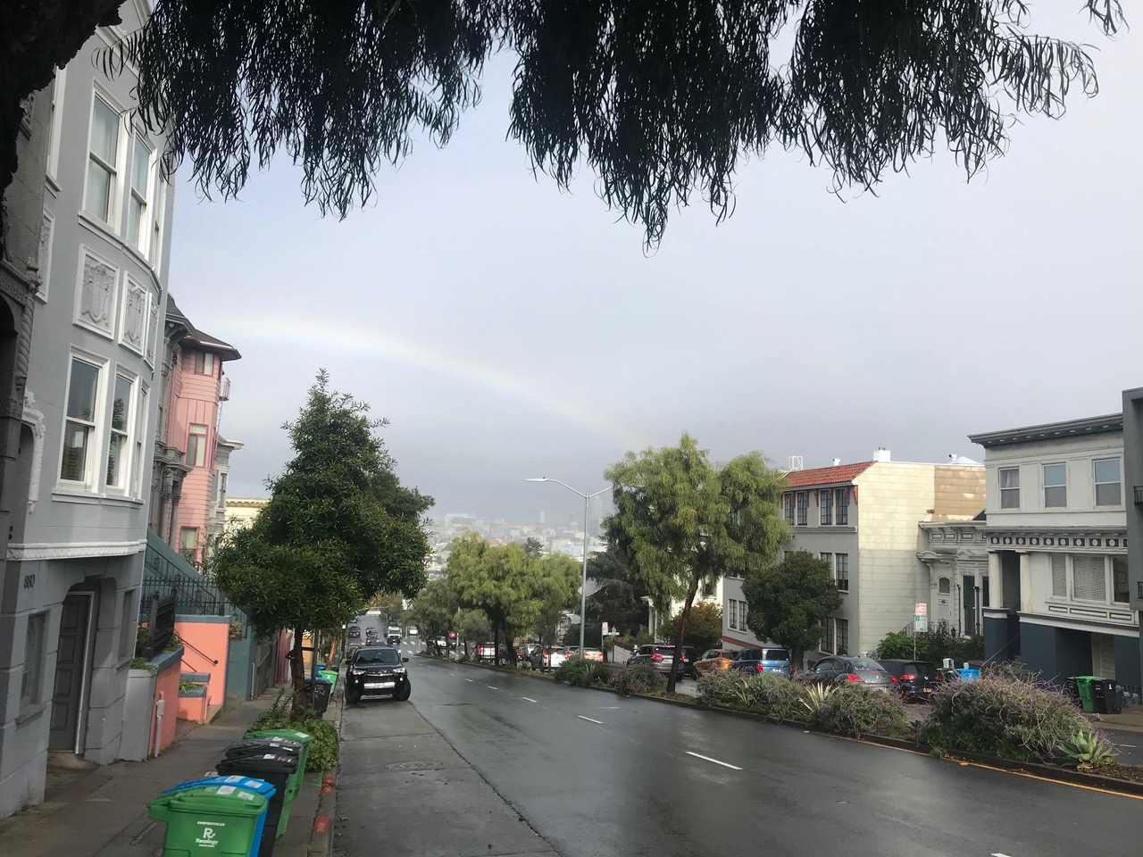 A rainbow is seen over a street in san francisco.