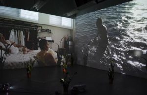 A room with a projection of a woman in a bathing suit.