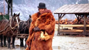 A man in a fur coat standing next to a horse.