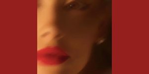 A blurred image of a woman's face with red lipstick.