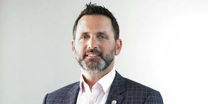 A man wearing a suit and a pink shirt.