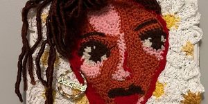 A crocheted portrait of a woman with dreadlocks.