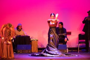 A woman performs a flamenco dance on stage.