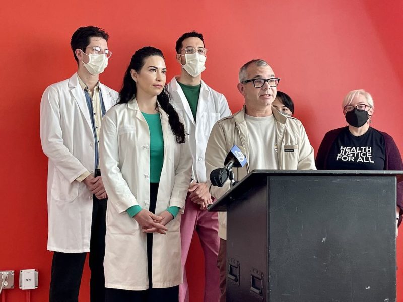 A group of people standing at a podium with masks on.