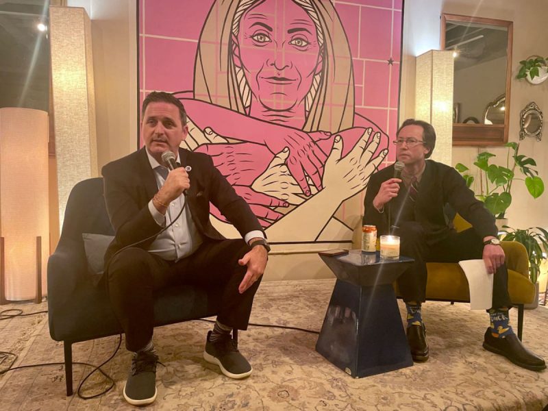 Two men sitting in chairs with microphones.