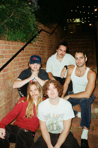 A group of men posing in front of a brick wall.
