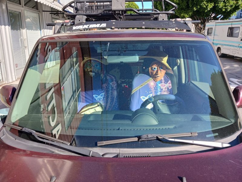 A red vehicle with a sculpture of a person in the driver's seat.