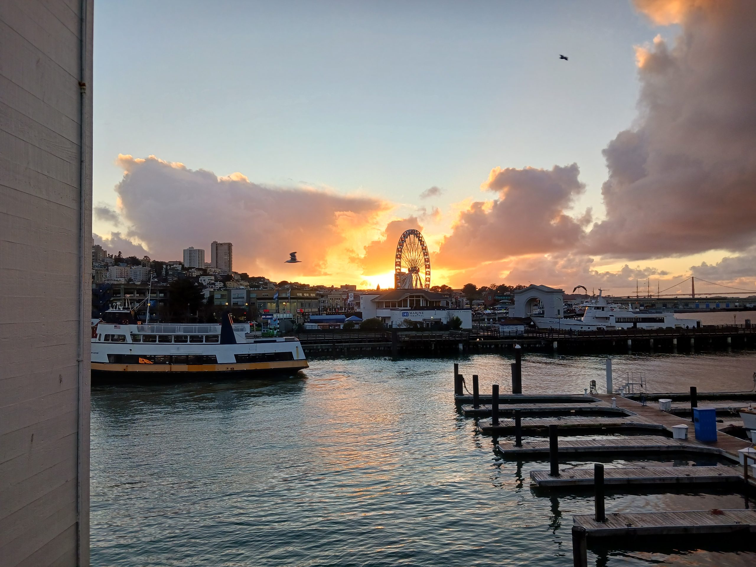 A boat docked at a dock with a ferris wheel in the background.