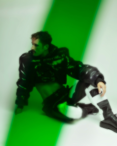 A man sitting on the ground with a green background.