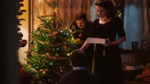 A man and woman are putting presents under a christmas tree.