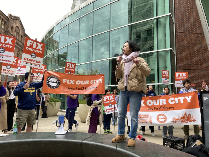 A woman speaking into a microphone in front of a group of people.