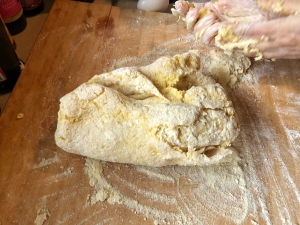 A person kneading dough on a wooden table.