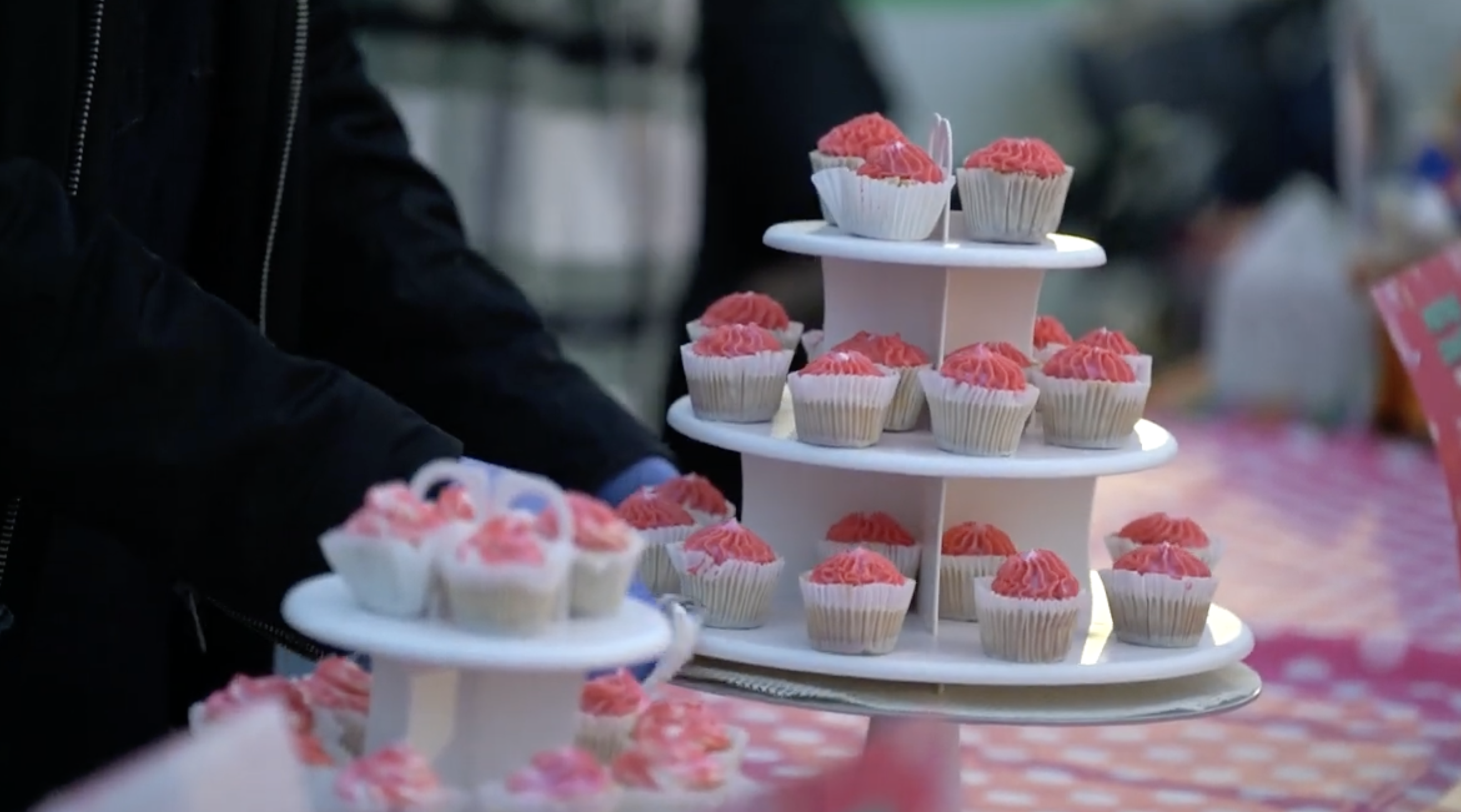 A person is holding cupcakes on a table.