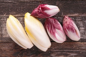 Four different kinds of radishes on a wooden background.