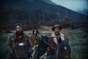Three men riding horses in a field.