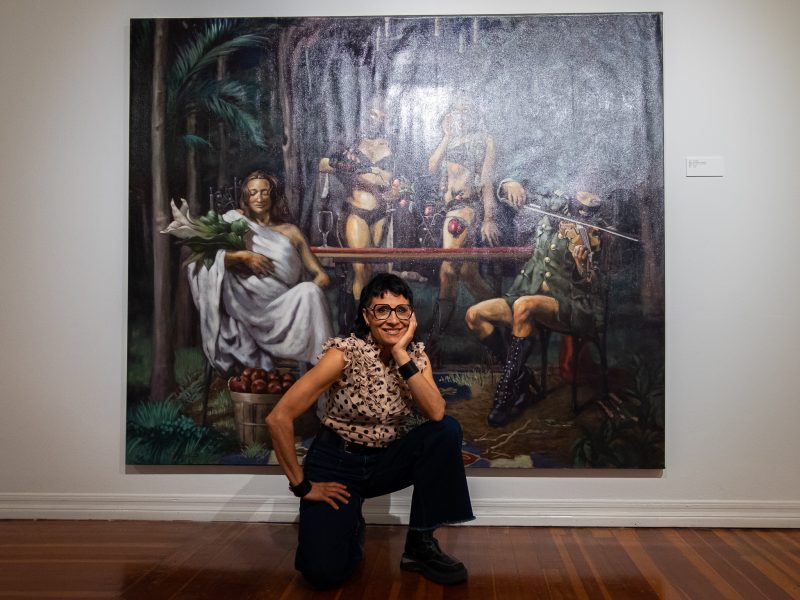 A woman crouching in front of a painting.