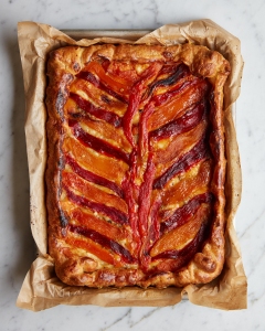A tart with red and yellow peppers on top of a piece of paper.