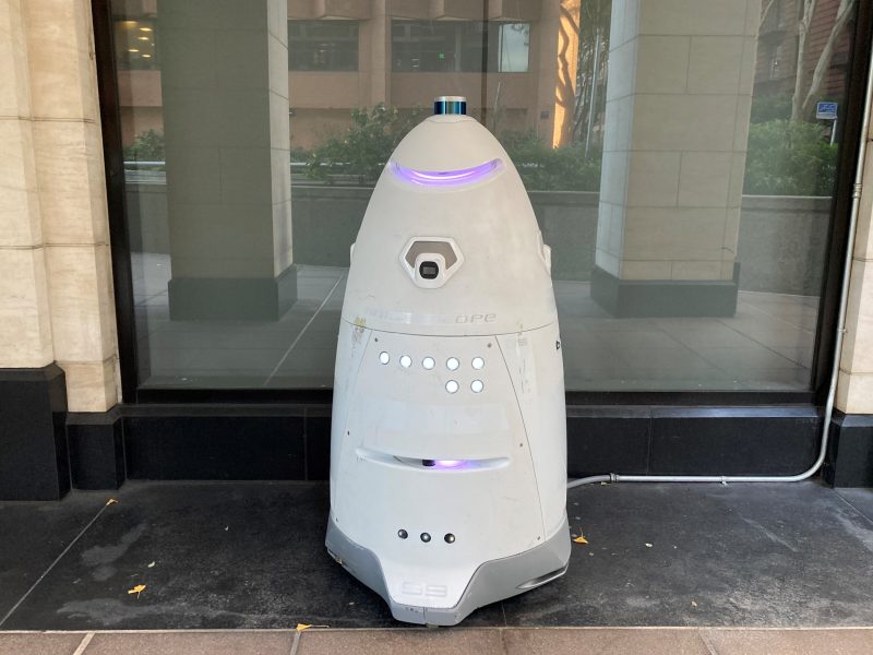 Autonomous security robot stationed in front of a building.