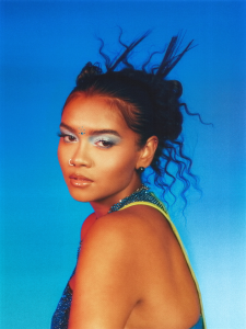 Woman with creative makeup and flowing hair against a blue background.