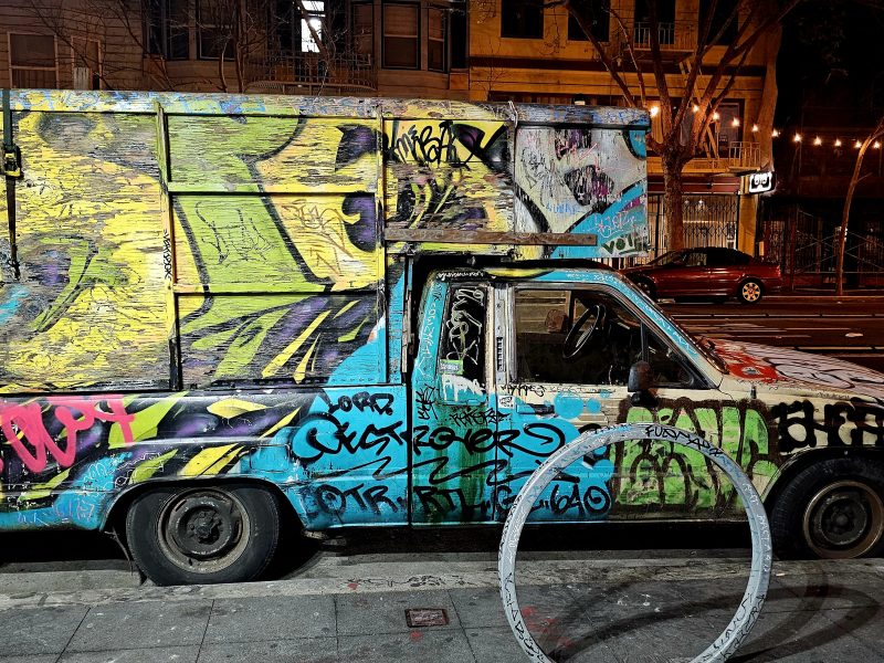 Van covered in graffiti parked on an urban street at night.