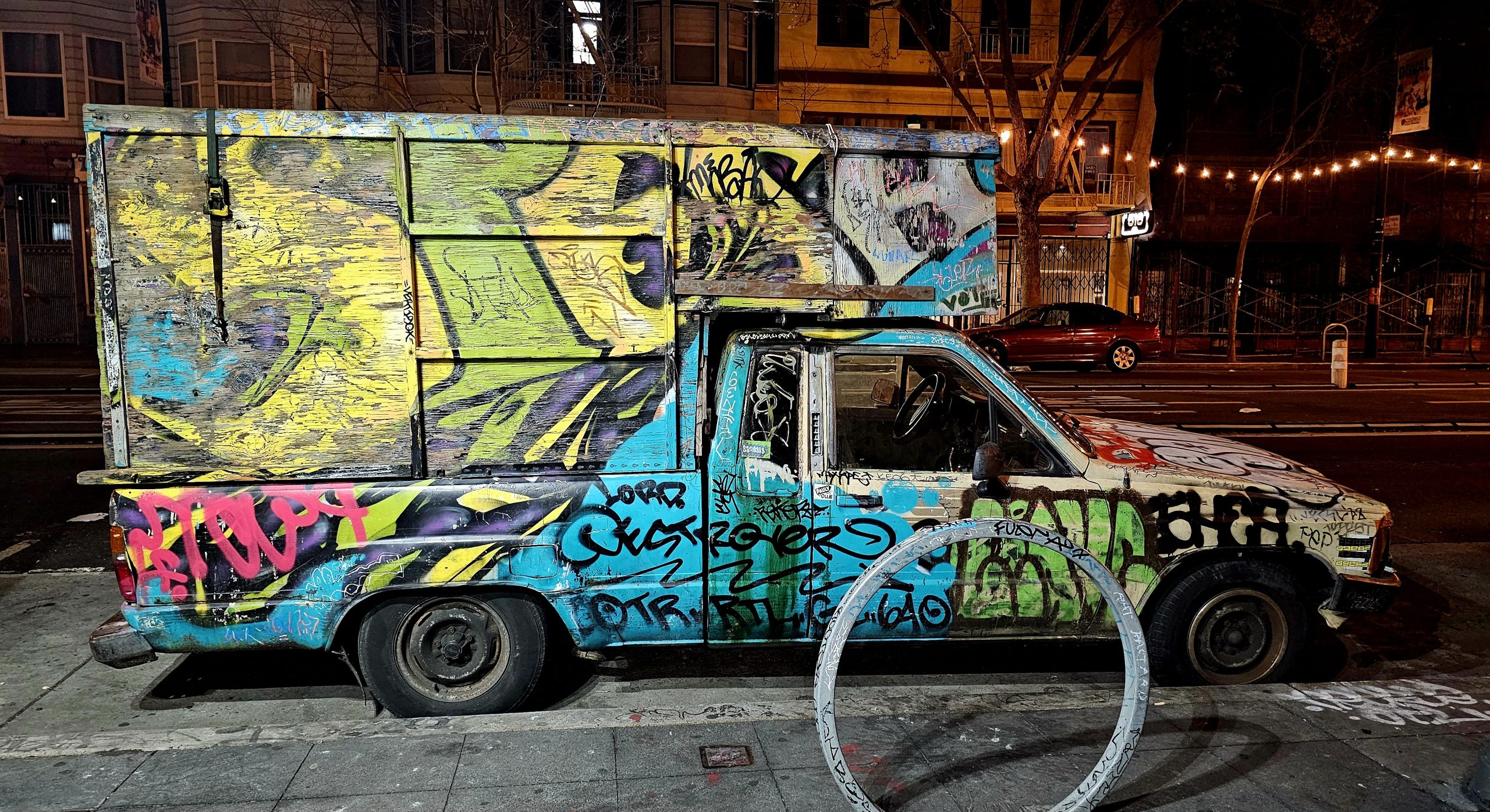 Van covered in graffiti parked on an urban street at night.