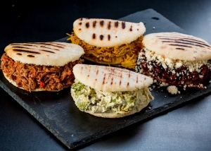 Three different types of filled arepas on a slate serving platter.