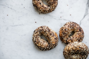 Three bagels with sesame seeds on a marble table.