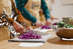Preparing ingredients: chopping red cabbage on a cutting board in a cooking class.