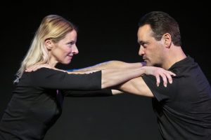Two actors performing a confrontational scene on stage.