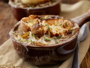 French onion soup with melted cheese and croutons in a ceramic bowl.