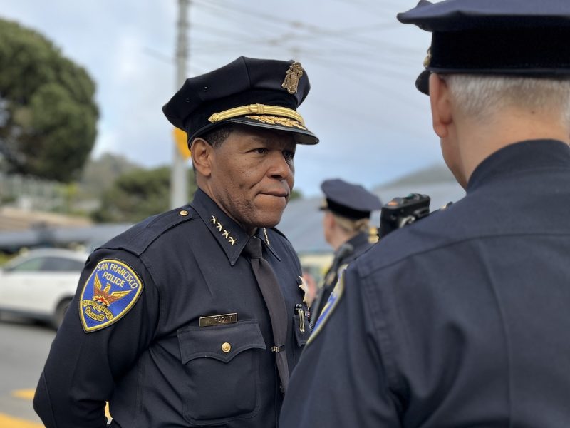 A police officer in uniform engaging in a conversation with a colleague outdoors.