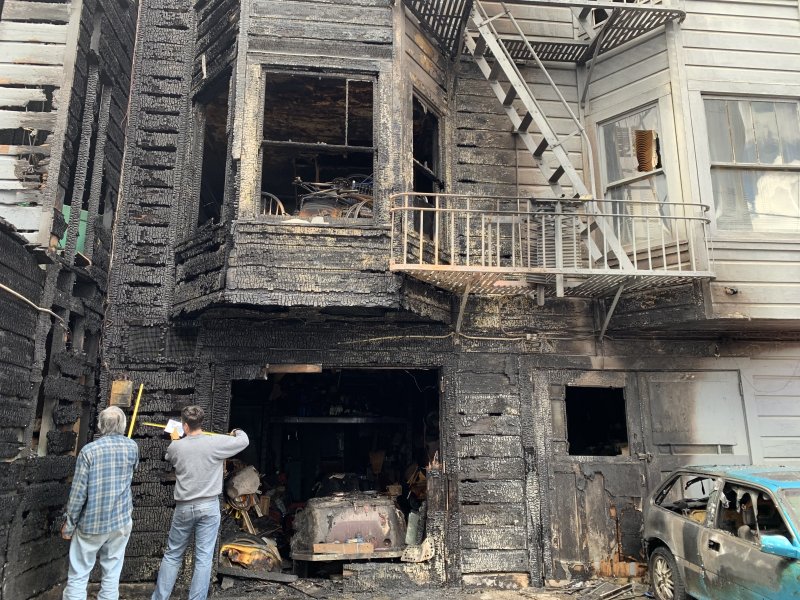 Two men standing before a burned out structure