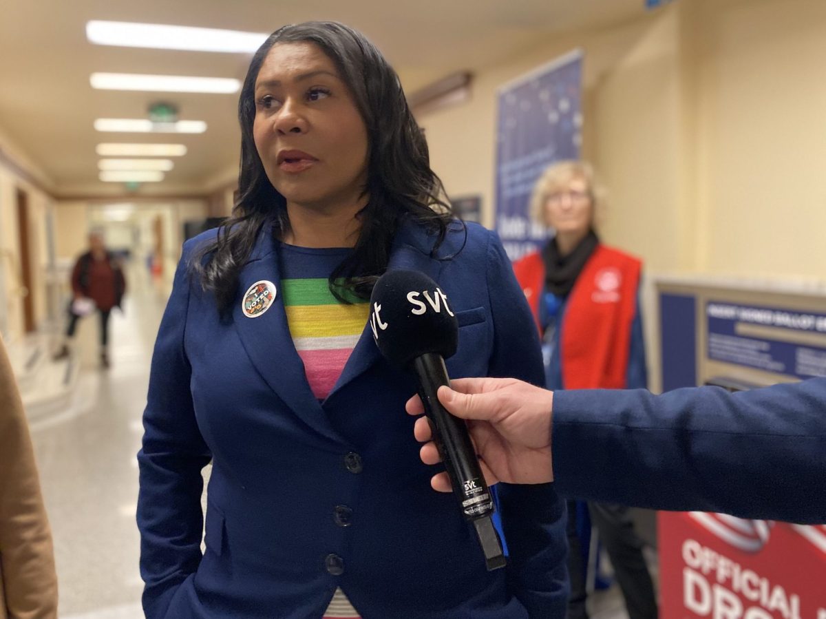 Mayor London Breed, speaking into a microphone at City Hall
