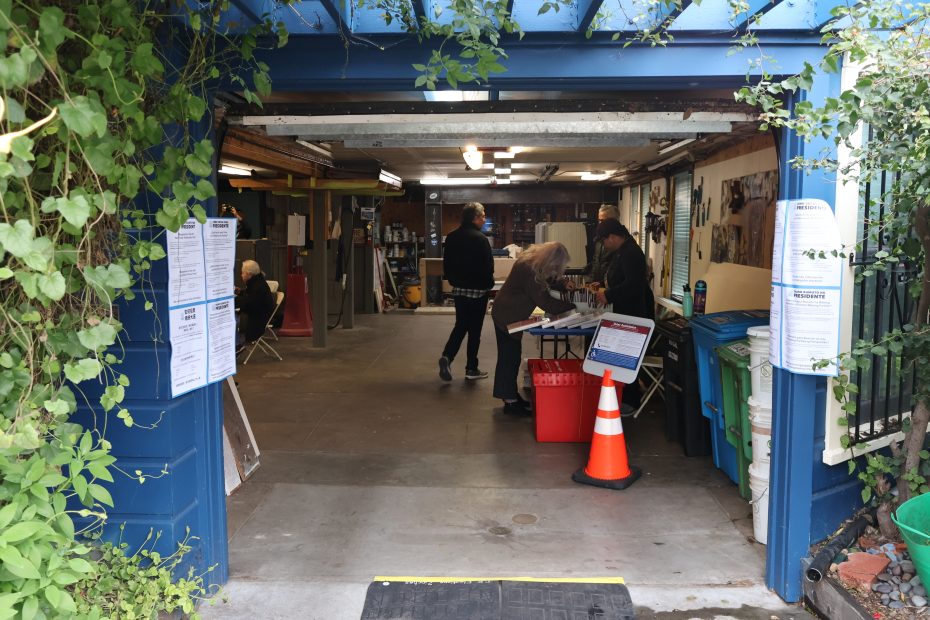 A group of people standing in front of a blue garage door during an election.