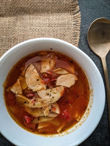 Bowl of vegetable soup with a spoon on the side.