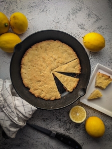 Lemon bread in a skillet with lemons and a knife.