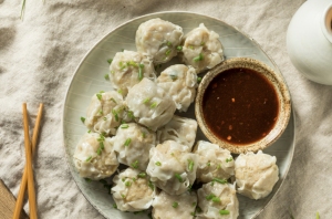 Dumplings with dipping sauce on a plate.