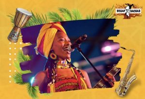 A vibrant music-themed graphic with an image of a smiling woman singing into a microphone, flanked by illustrations of a drum and a saxophone, against a yellow background with tropical leaves and the words .
