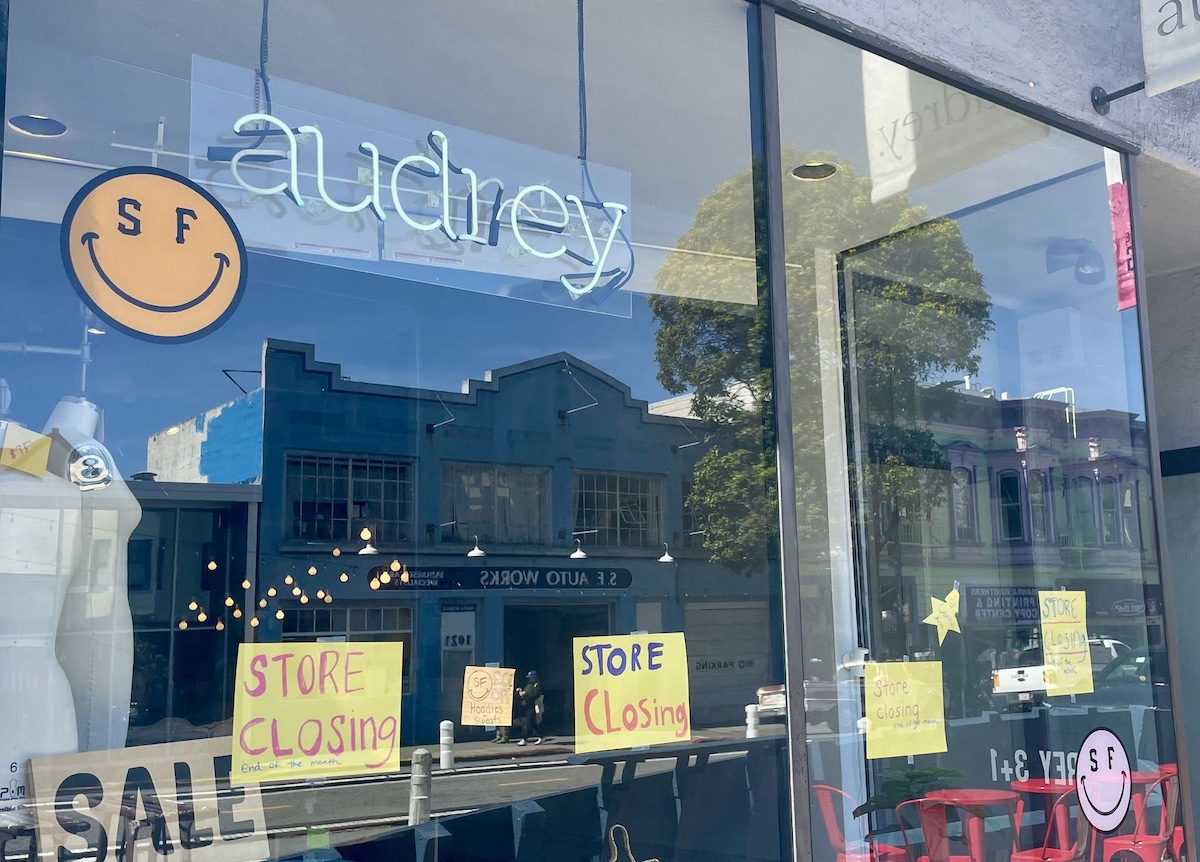 Audrey storefront window with "store closing" signs and reflections.