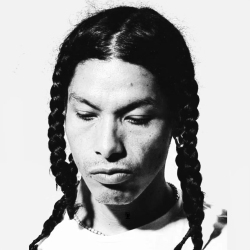 A monochrome portrait of a person with braided hair and a contemplative expression.