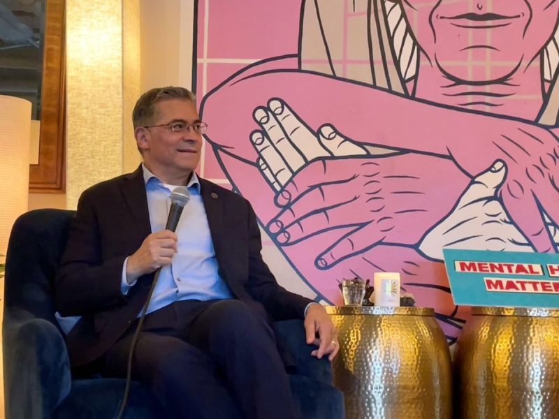 A man sitting on a couch holding a microphone is HHS Secretary Xavier Becerra.