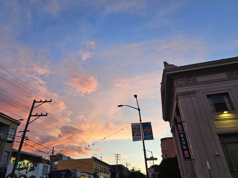 Dusk over a city street with a pink and blue sky.