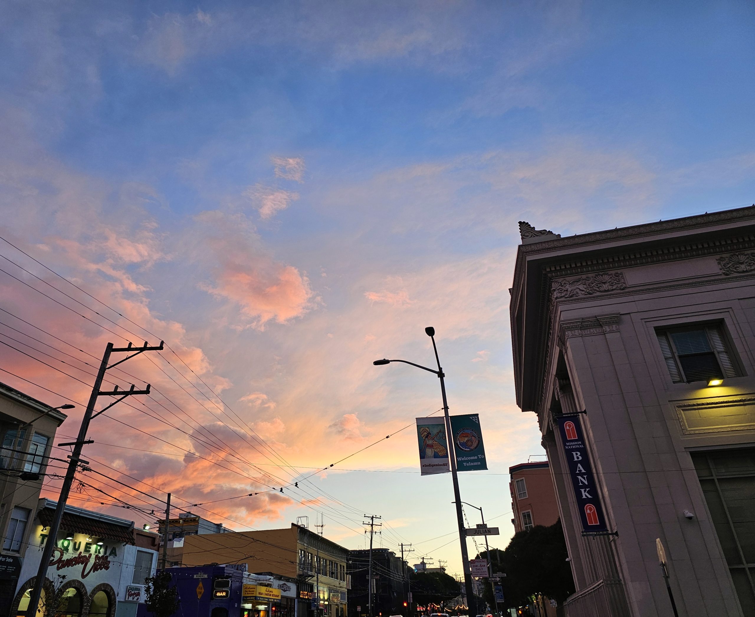 Dusk over a city street with a pink and blue sky.