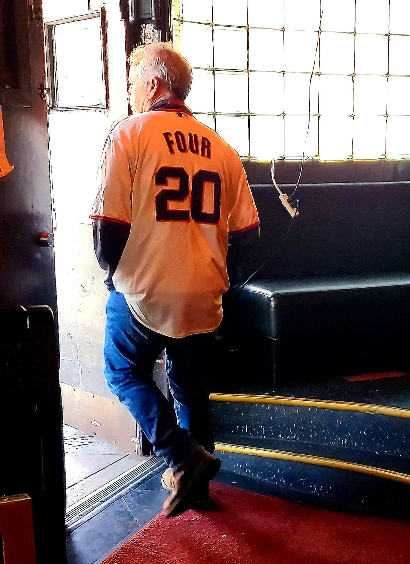A man wearing a shirt that says "FOUR 20", exiting through the door.
