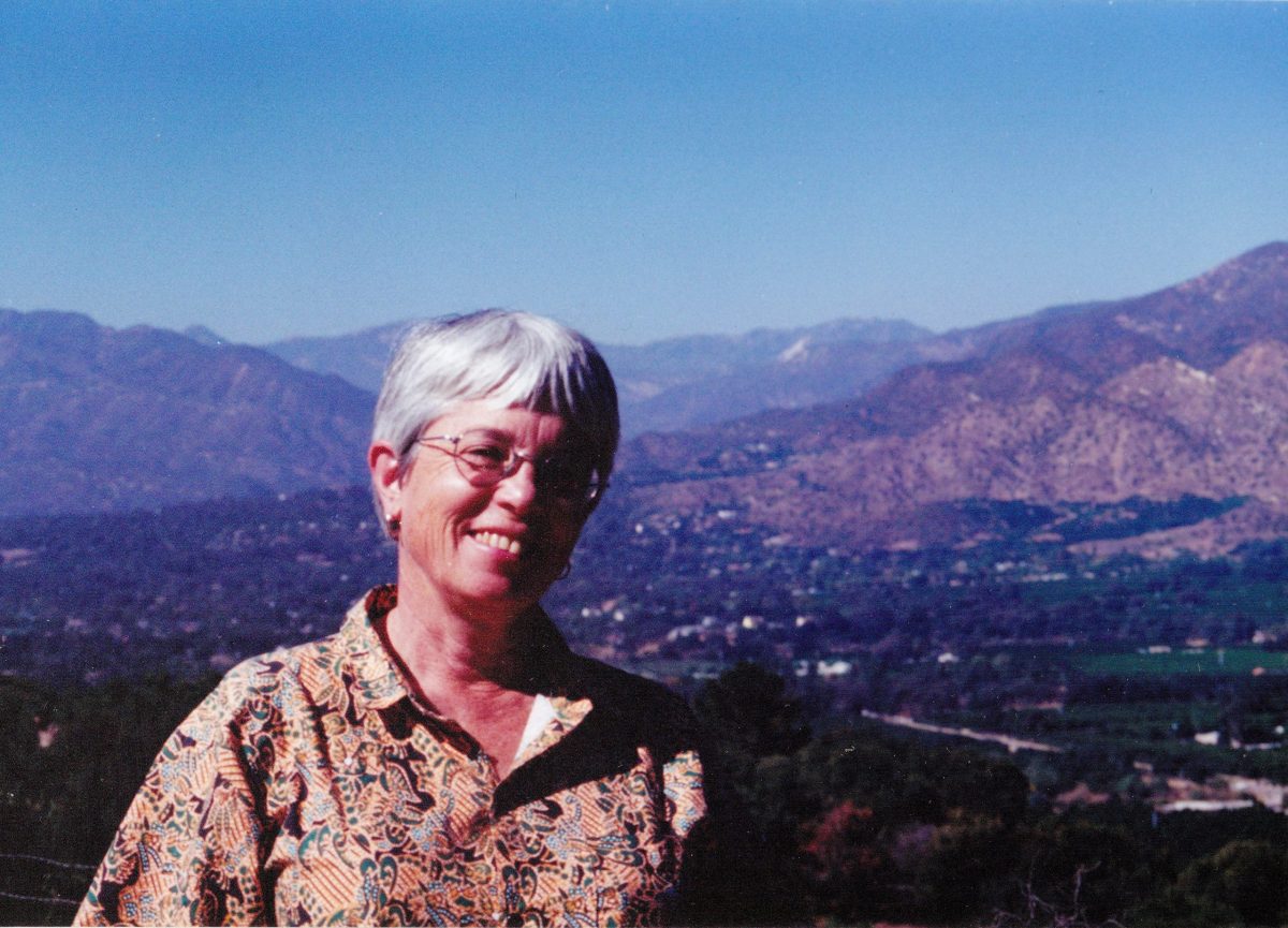 Joan Holden posses for a photo with a city and mountains in the background.