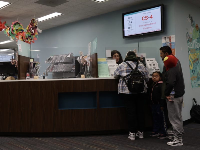 A reception area in Room 100 with a family speaking to a staff member behind the counter.
