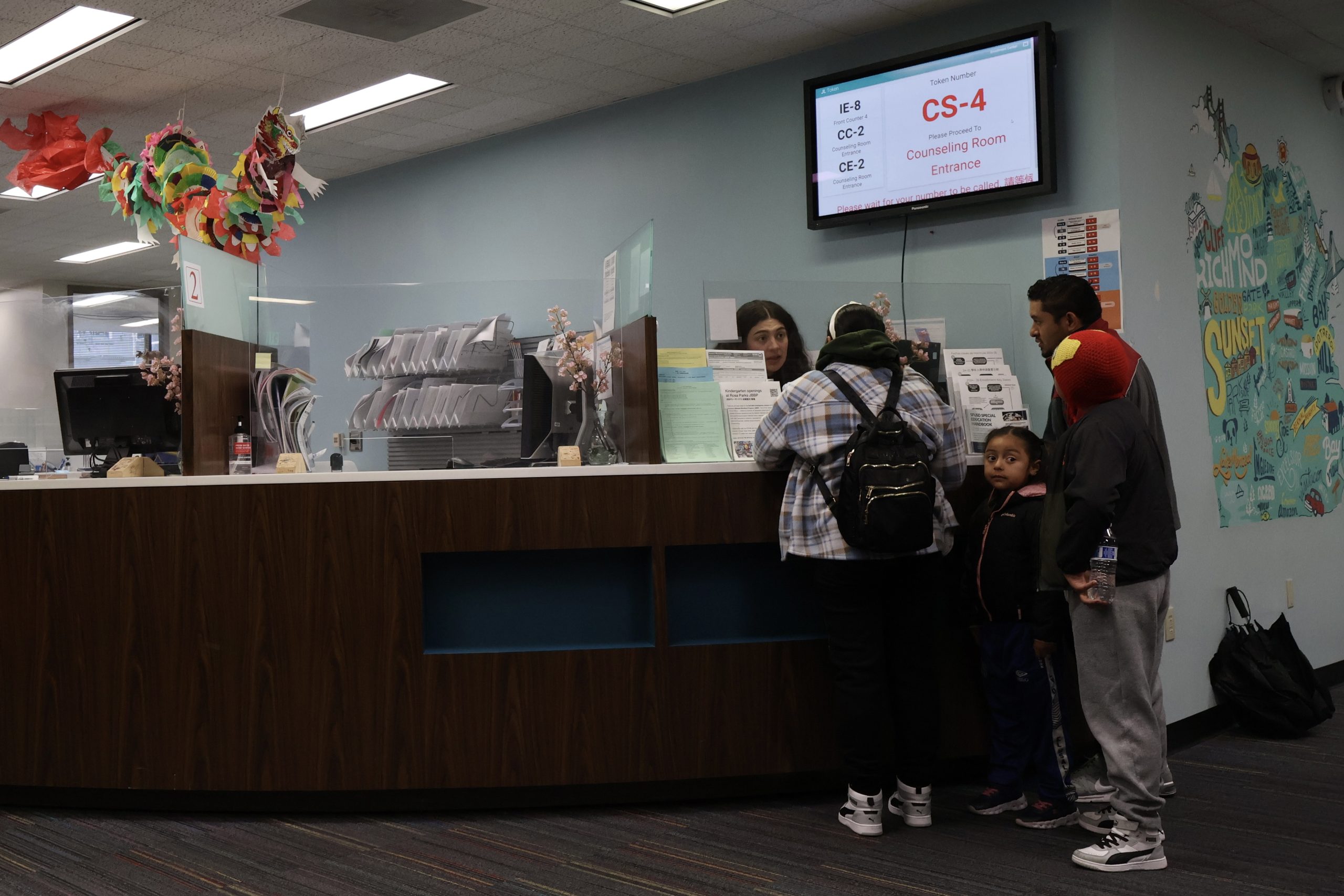 A reception area in Room 100 with a family speaking to a staff member behind the counter.